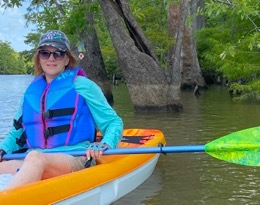 A smiling paddler in an orange kayak